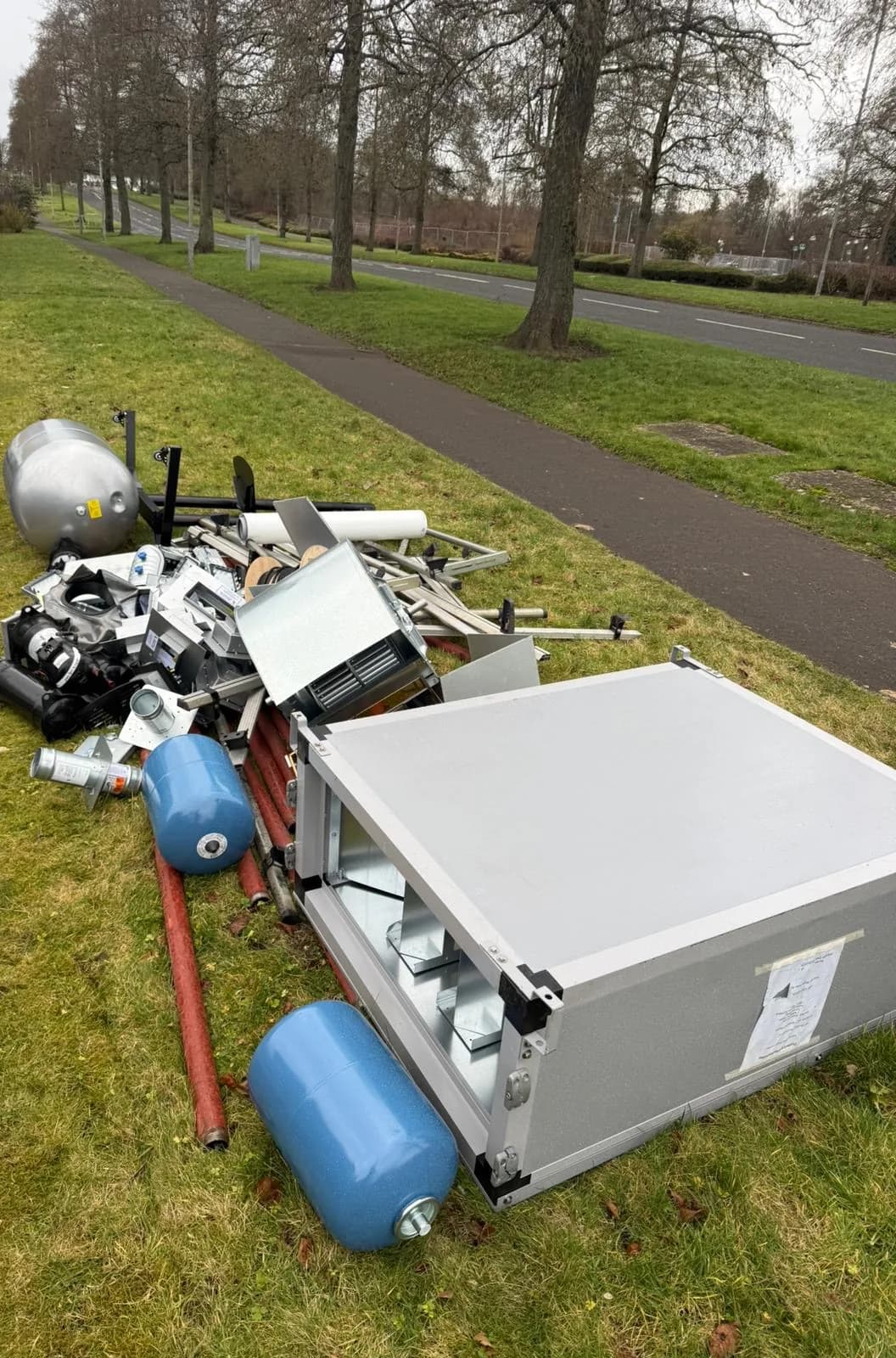 Air handling unit, expansion vessels and pipework on a grass verge beside a road