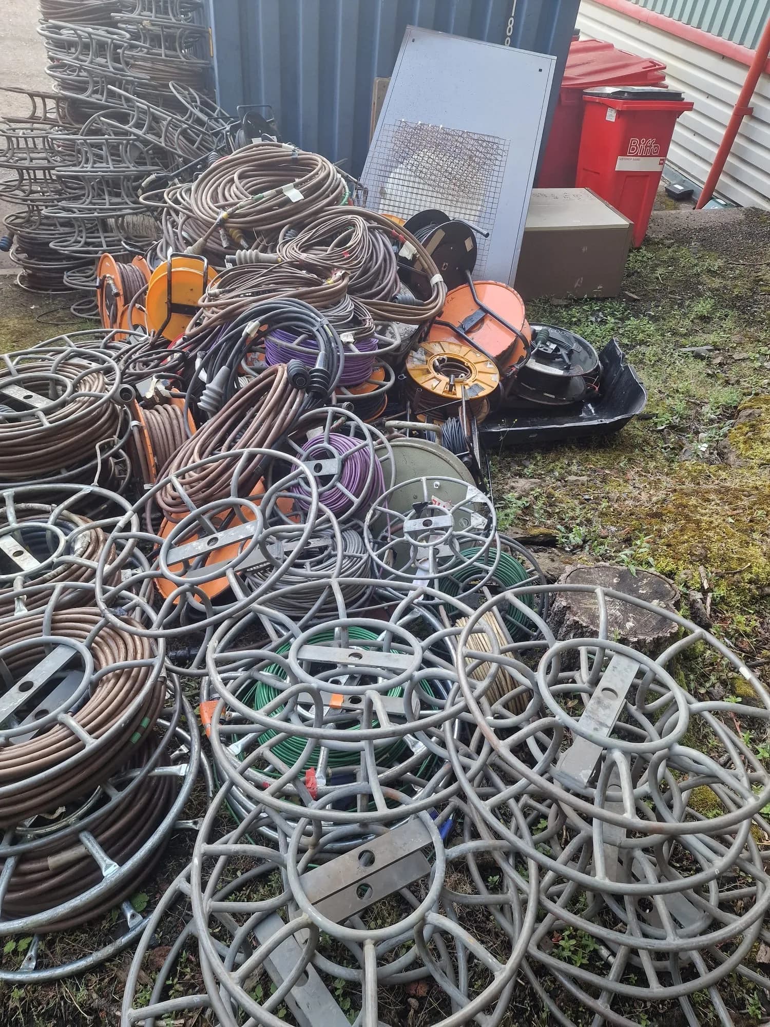 Dozens of cable reels and coils piled outside a warehouse