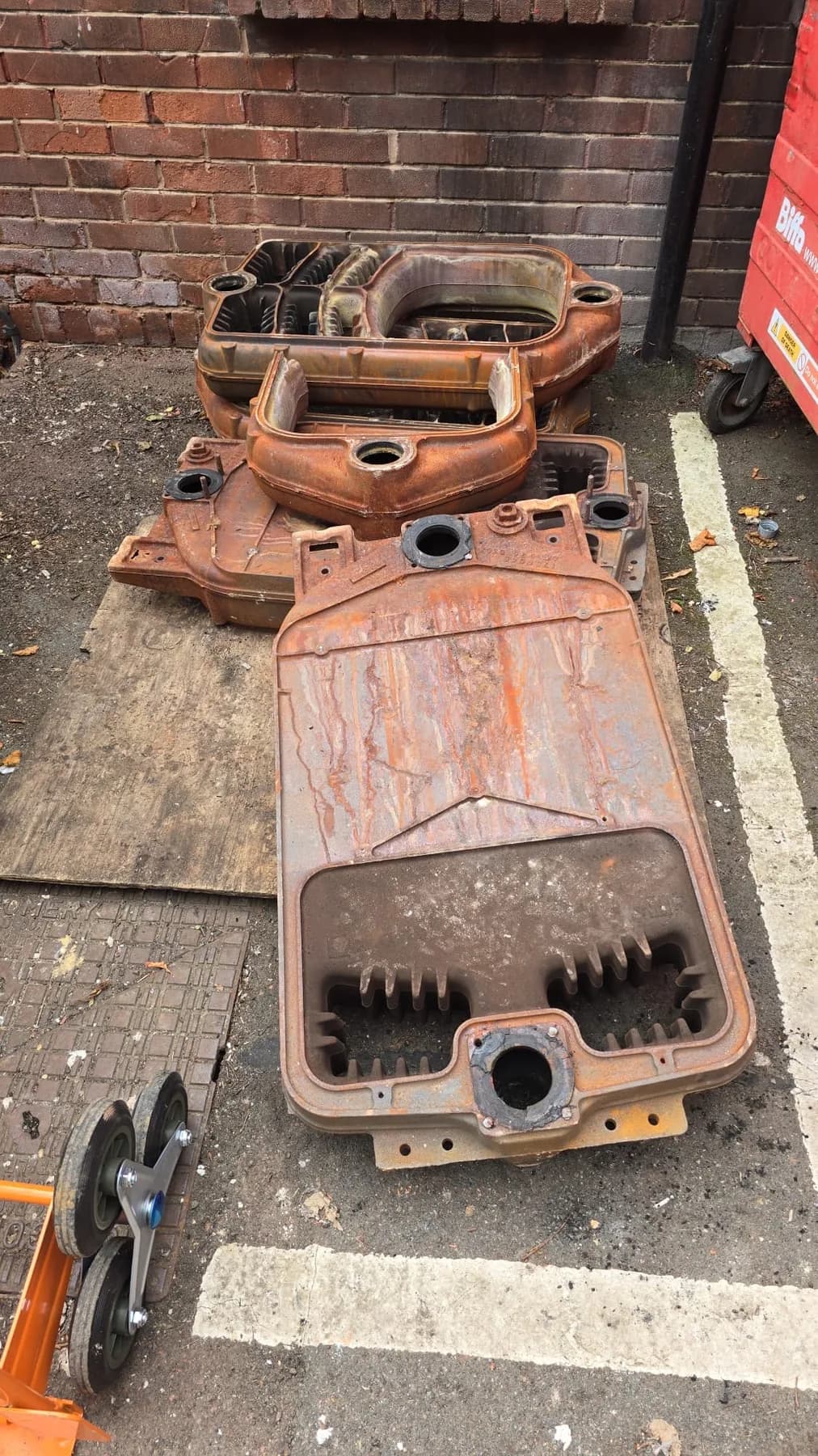 Rusted cast iron boiler sections laid out on a pavement