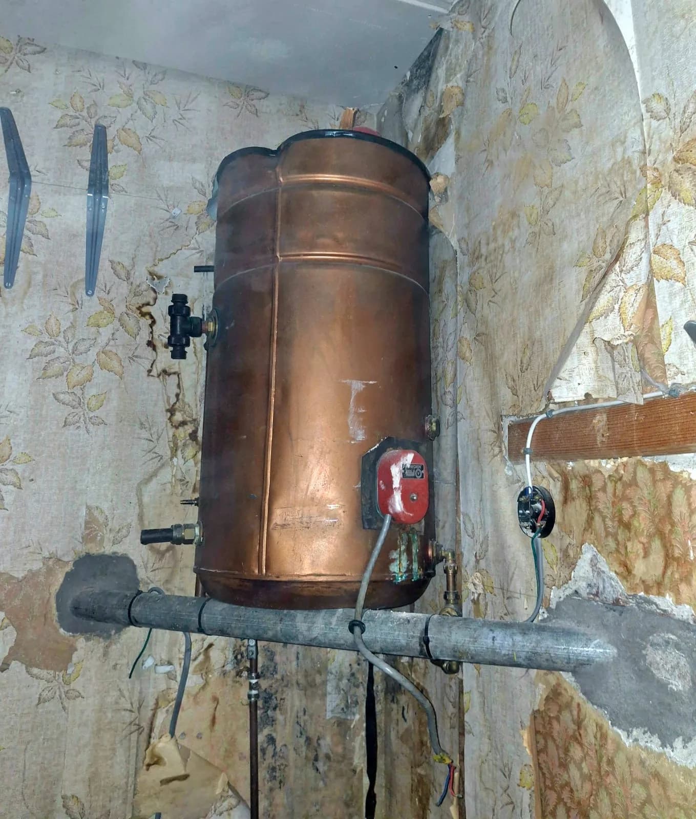Copper hot water cylinder in a cupboard with the pipework still attached