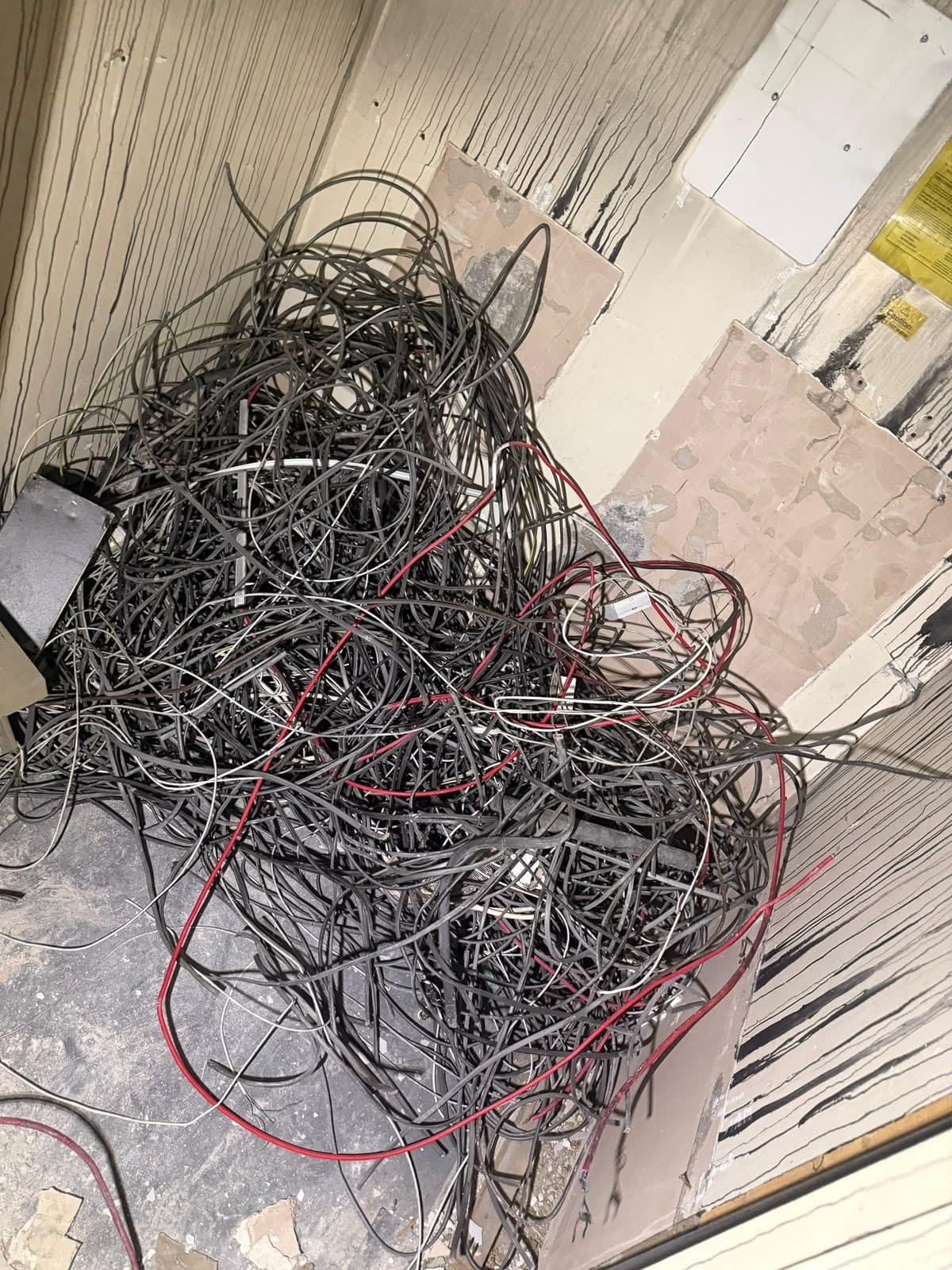 A large tangle of stripped-out electrical cable on the floor of a gutted room