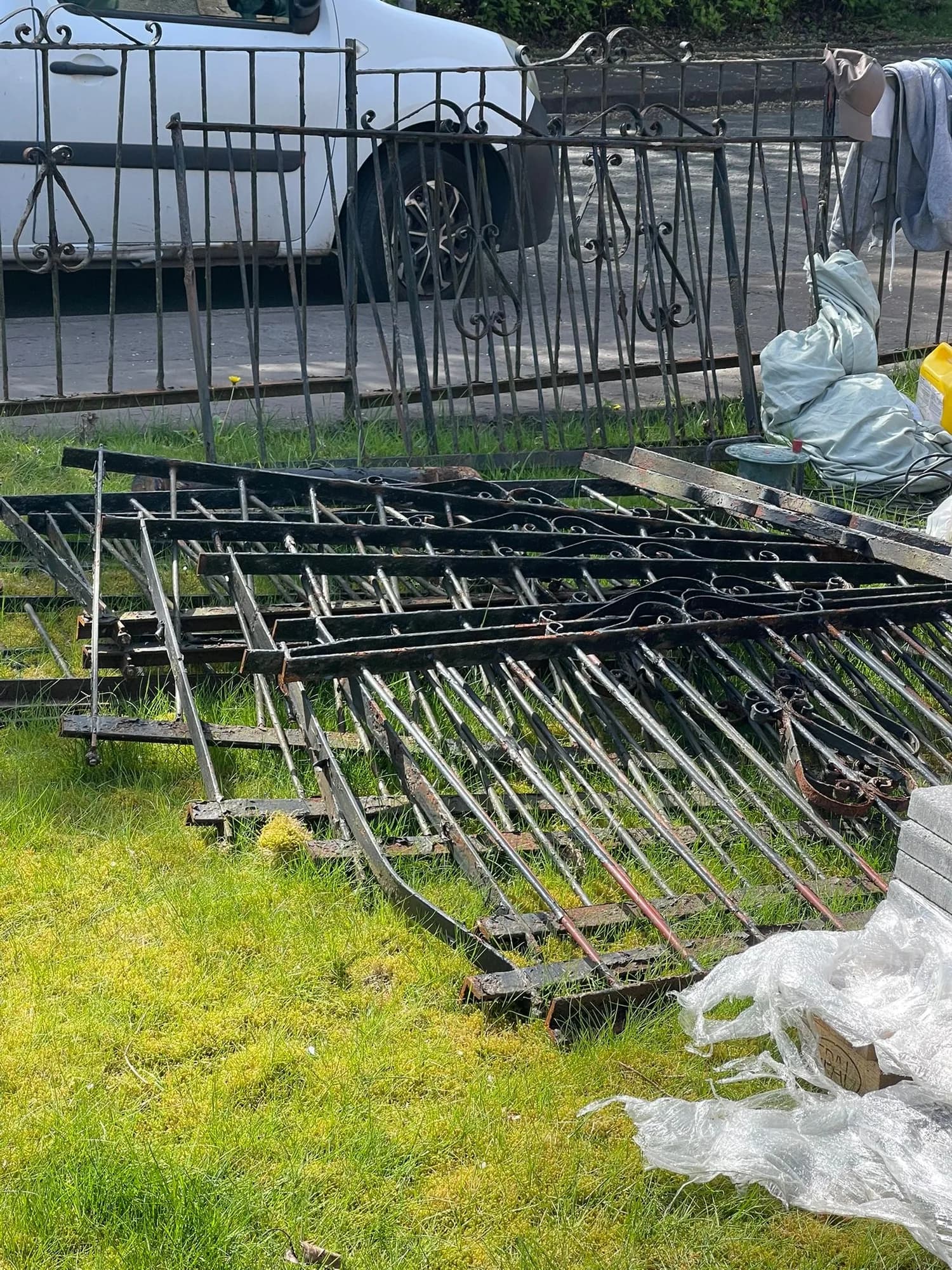 Wrought iron railings laid on a lawn beside a white van